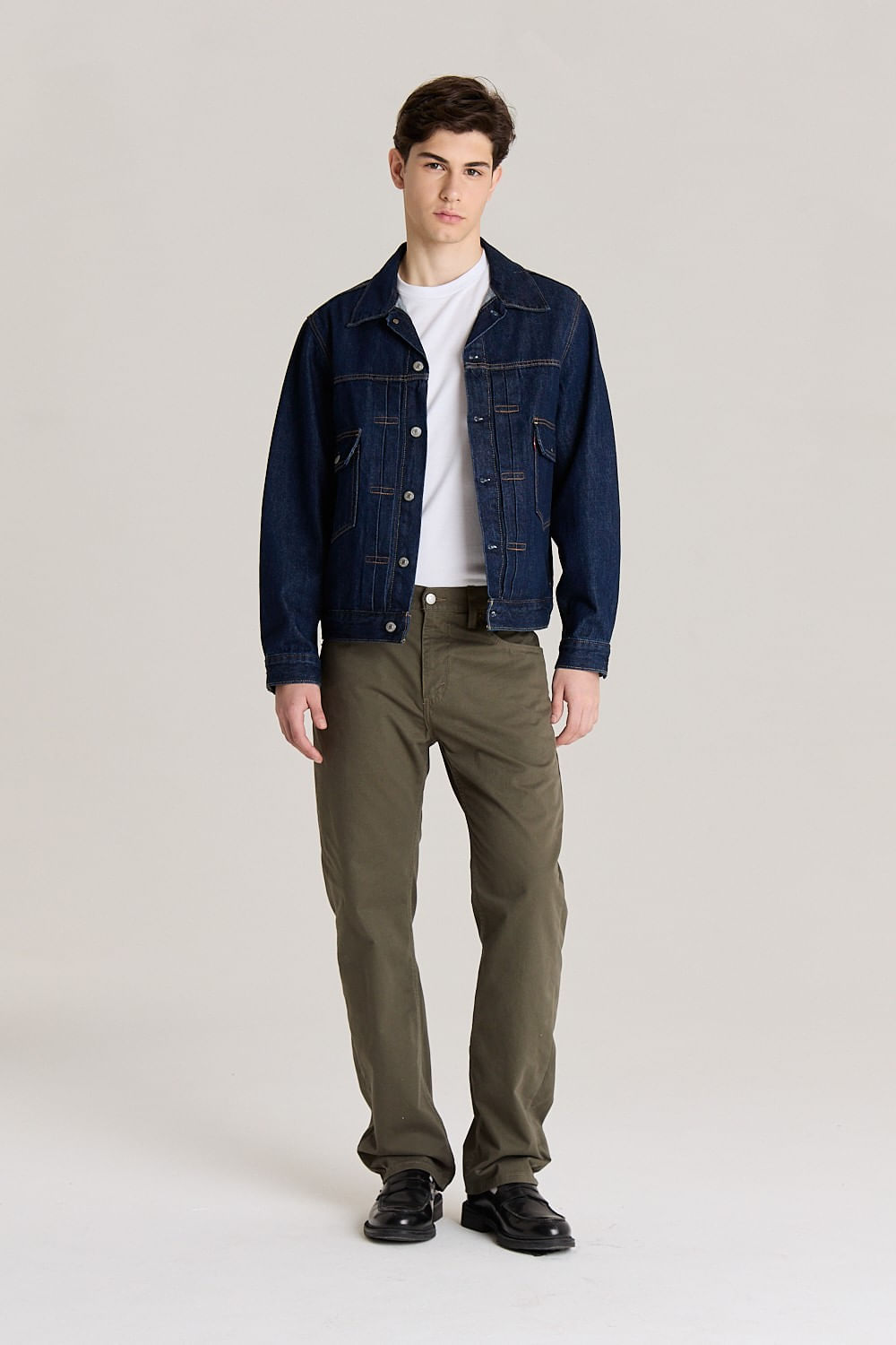 Hombre con chaqueta de mezclilla y pantalones verdes.